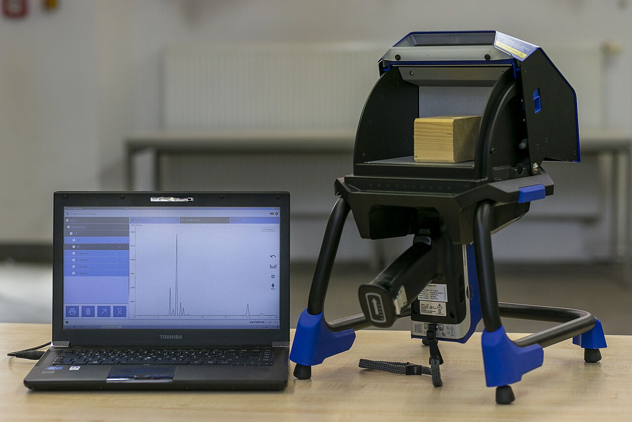 Gerät zur Röntgenfluoreszenzanalyse von Holz, daneben ein Laptop, auf dem die Analysen angezeigt werden.